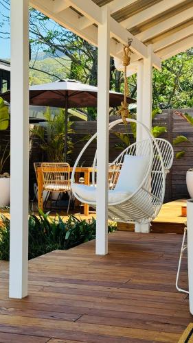 a porch with white chairs and an umbrella at Wombarra Luxe Cottage in Wombarra
