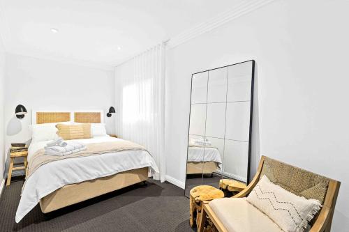a bedroom with a bed and a mirror and a chair at Wombarra Luxe Cottage in Wombarra