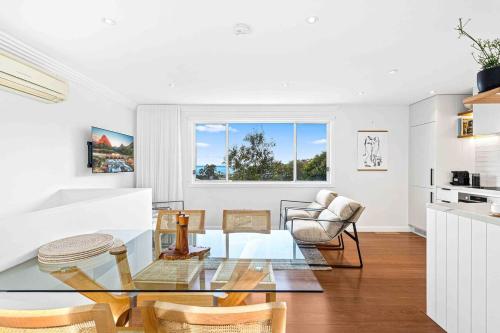 a living room with a glass table and chairs at Wombarra Luxe Cottage in Wombarra