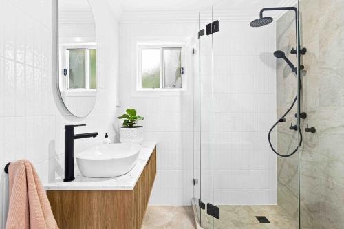 a bathroom with a sink and a shower at Wombarra Luxe Cottage in Wombarra