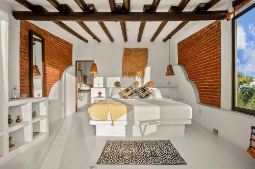 a bedroom with a white bed and a brick wall at Private 5-Bedroom Compound with Pool Tepoztlán Retreat in Tepoztlán