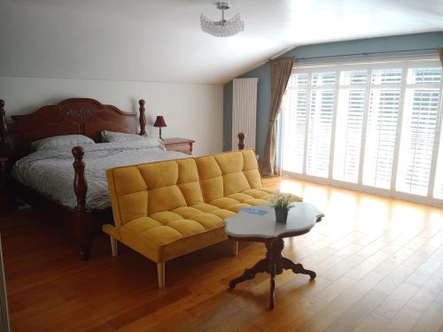 a bedroom with a bed and a yellow couch at Cosy Rural Gilbert Hights Llandovery Cynghordy in Cynghordy