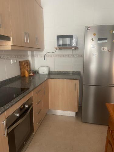 una cucina con frigorifero in acciaio inox e forno a microonde di Acogedor piso en Benissanó a Benisanó
