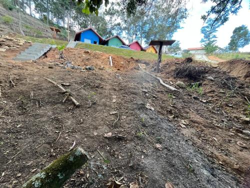a dirt field with a house in the background at Chalés do vale Extrema vermelho in Extrema