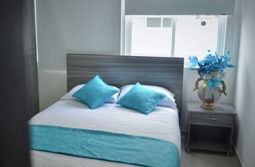 a bed with blue pillows in a bedroom with a window at Hotel Éxito Pereira Center in Pereira