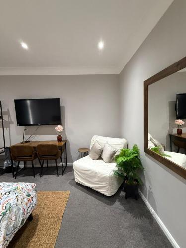 a living room with a white couch and a mirror at Alross Guest House with Italian Breakfast in London