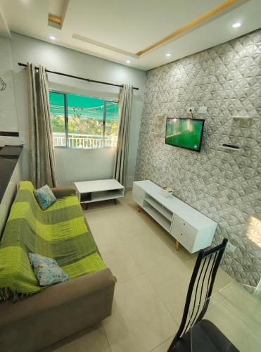 a living room with a couch and a tv on a wall at Apartamento charmoso in Pirassununga