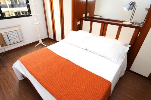 Un dormitorio con una cama con una manta naranja. en Barrabella Apart Hotel, en Río de Janeiro