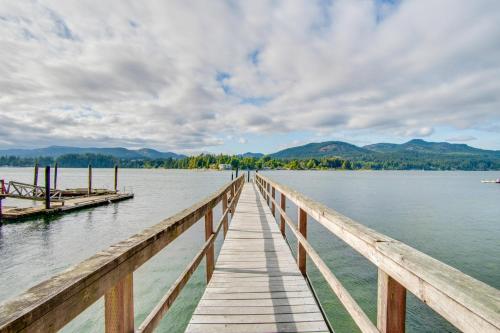 a wooden dock on a lake with mountains in the background at Oceanfront Getaway in Sooke