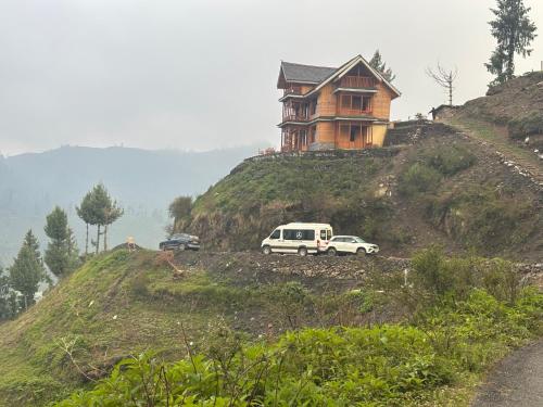 a house on a hill with cars parked in front of it at Apple Land by Naavagat in Jibhi
