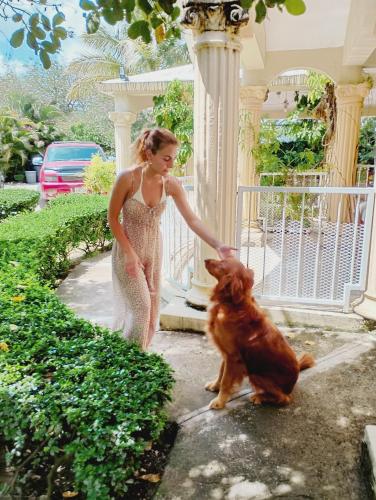 a woman is petting a dog in front of a house at Paraíso Hortensia Honeymoon Suite in Santiago de los Caballeros