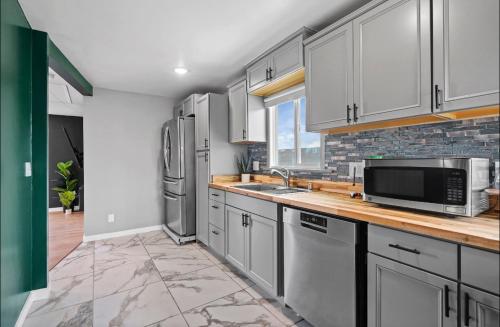 a kitchen with white cabinets and stainless steel appliances at Twilight Terrace - Telescope - 15 Min to Beach in Hawthorne