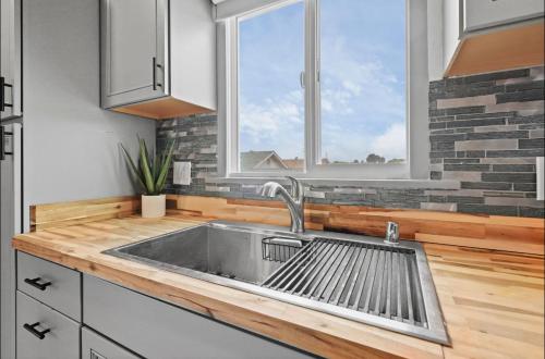 a kitchen with a stainless steel sink and two windows at Twilight Terrace - Telescope - 15 Min to Beach in Hawthorne