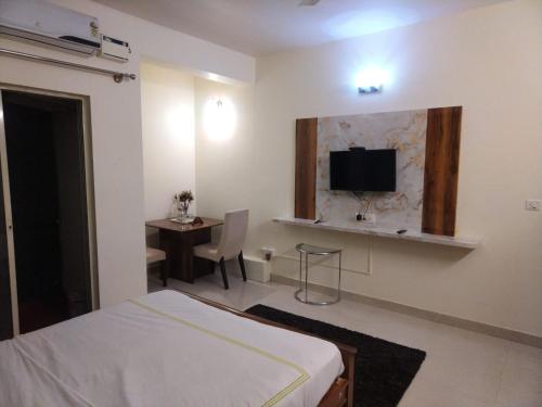 a bedroom with a bed and a tv on the wall at SAS Apartment in Bengaluru