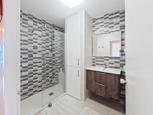 une salle de bain avec un lavabo et une douche dans l'établissement Appartement T2 rénové face à la mer avec terrasse et garage - Quartier des Présidents - Les Sables-d'Olonne - FR-1-331-90, à Les Sables-dʼOlonne