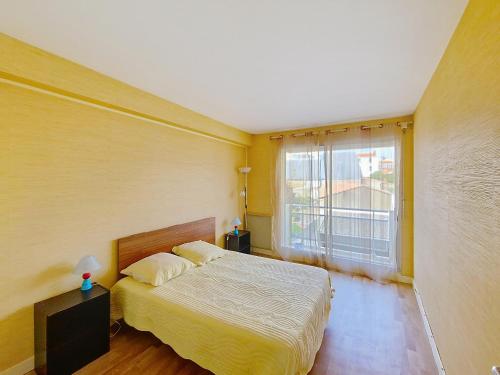 une chambre avec un lit et une grande fenêtre dans l'établissement Appartement lumineux 2 pièces à 100 m de la plage et du marché Arago, avec balcon et parking sécurisé - FR-1-331-100, à Les Sables-dʼOlonne