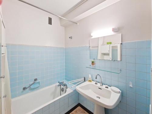 La salle de bains bleue et blanche est pourvue d'un lavabo et d'une baignoire. dans l'établissement Appartement lumineux 2 pièces à 100 m de la plage et du marché Arago, avec balcon et parking sécurisé - FR-1-331-100, à Les Sables-dʼOlonne