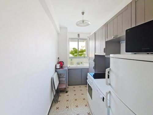 une cuisine avec un réfrigérateur blanc et une fenêtre dans l'établissement Appartement lumineux 2 pièces à 100 m de la plage et du marché Arago, avec balcon et parking sécurisé - FR-1-331-100, à Les Sables-dʼOlonne