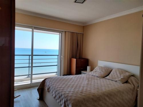 une chambre avec un lit et une grande fenêtre dans l'établissement T3 face mer avec balcon - 3ᵉ étage, 100 m du centre - 6 personnes - Garage - Plage au pied - FR-1-331-101, à Les Sables-dʼOlonne