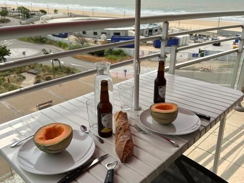 une table avec deux bouteilles de bière et des paniers de pain dans l'établissement Studio moderne 4 pers, balcon et plage à 50m - FR-1-323-423, à Saint-Jean-de-Monts