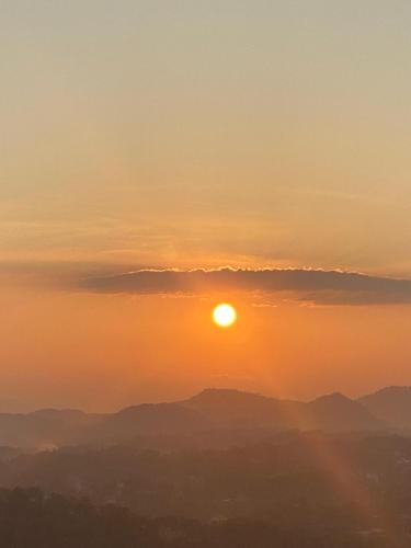 a sunset over mountains with the sun in the sky at The Space Garden Hotel Kandy in Nikawatawana