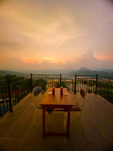 a table and chairs on a balcony with a sunset at The Space Garden Hotel Kandy in Nikawatawana