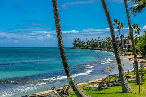 a beach with palm trees and chairs and the ocean at Paki Maui #103 condo in Kahana