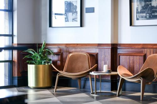 a room with three chairs and a potted plant at Powerhouse Hotel Tamworth by Rydges in Tamworth