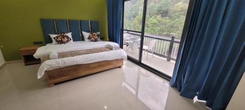 a bedroom with a bed and a balcony with a view at Hotel MountMemory , Barkot-Yamunotri in Barkot