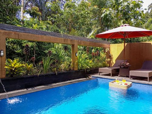 a swimming pool with an umbrella and a chair and a table and an umbrella at Anggi Villas Ubud in Tegalalang
