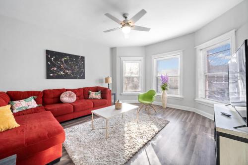 a living room with a red couch and a ceiling fan at Cozy Woodlawn Retreat 2 in Chicago