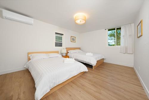 two beds in a bedroom with white walls and wood floors at remodeled 2b 1b house Rosemead c in Rosemead