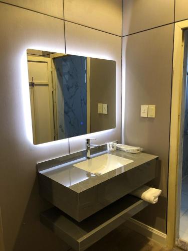 a bathroom with a sink and a large mirror at العنوان للشقق المخدومة ALanwaan of the units served in Dammam