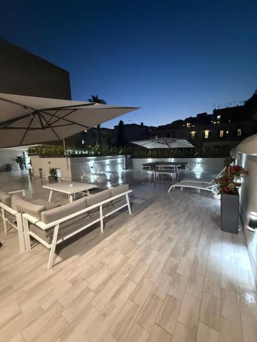 a rooftop patio with benches and umbrellas at night at Palazzo Valentino in Naples