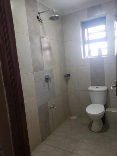 a bathroom with a toilet and a shower with a window at Syokiton Private Home near JKIA Airport in Syokimau