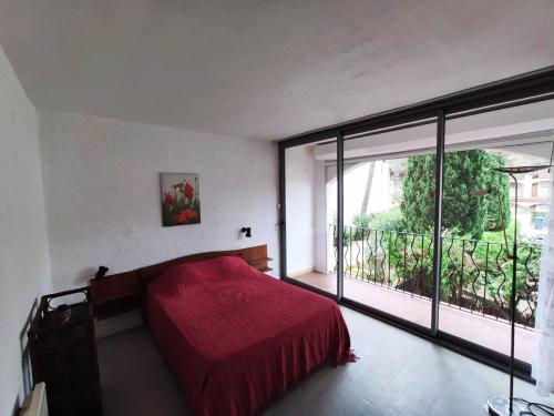 une chambre avec un lit rouge et une grande fenêtre dans l'établissement Appartement avec piscine, parking proche plage - FR-1-837-19, à Argelès-sur-Mer