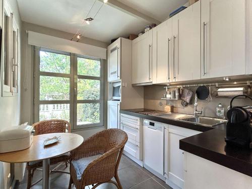 une cuisine avec des armoires blanches et une table et des chaises dans l'établissement Maison cosy 2 pièces avec jardinet, La Baule Centre - FR-1-245-216, à La Baule