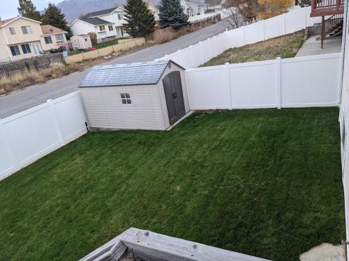 a backyard with a white fence and green grass at Beautiful Large Residential Home in Layton