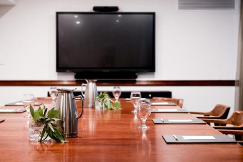 a large wooden table with wine glasses and a flat screen tv at Powerhouse Hotel Tamworth by Rydges in Tamworth