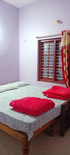 two red pillows sitting on a bed in a room at Coffee Heaven Homestay - near etthin bujja, devaramane, bettadhabiraveshvara temple in Mudigere