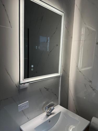 a white bathroom with a sink and a mirror at Hillside Haven in Kingston