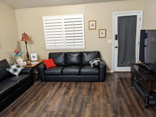 a living room with a black leather couch and a television at Beautiful Large Residential Home in Layton