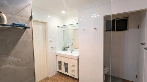 Un baño blanco con lavabo y ducha en Entire Place Private Luxe 1BR with 1BA 1K 1LR, en Ingleburn