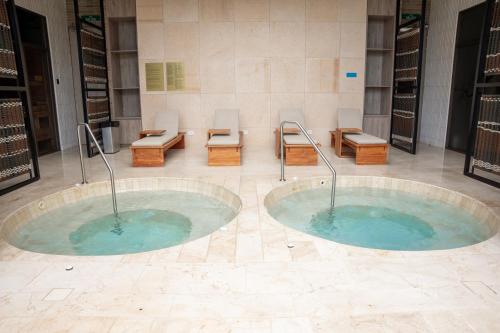 two hot tubs in a room with chairs and benches at Villa Puerta- Luxury Seaside Villa in Pendales