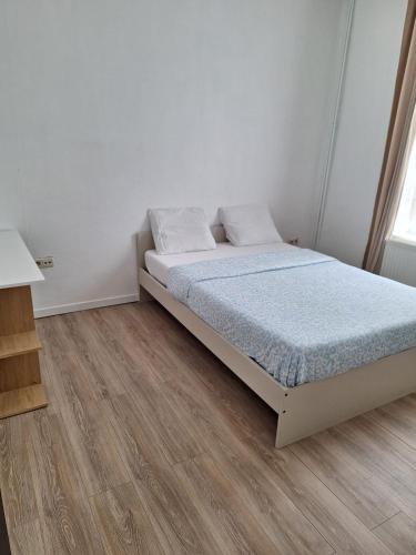 a white bedroom with a bed and a wooden floor at Maison sympathique in Liège