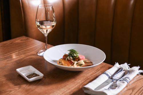 a plate of food and a glass of wine on a table at Powerhouse Hotel Tamworth by Rydges in Tamworth