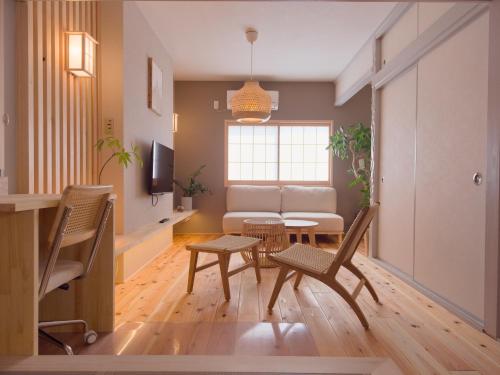 a living room with a couch and a table and chairs at Forest Japandi House in Osaka