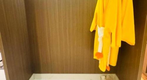 a bathroom with a yellow towel hanging on a wall at Shanshui Trends Hotel-Bantian Dong Branch in Shenzhen