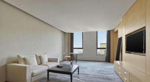 a living room with a white couch and a tv at Xian Elegant Oriental Hotel in Xi'an