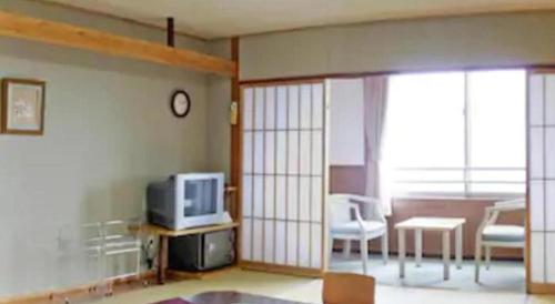a living room with a tv and a table and chairs at Kirishima Onsen Ryokojin Sanso in Kirishima